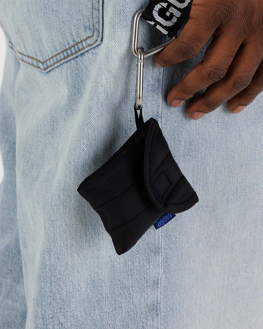 black puffy earbuds case hanging from models belt loop