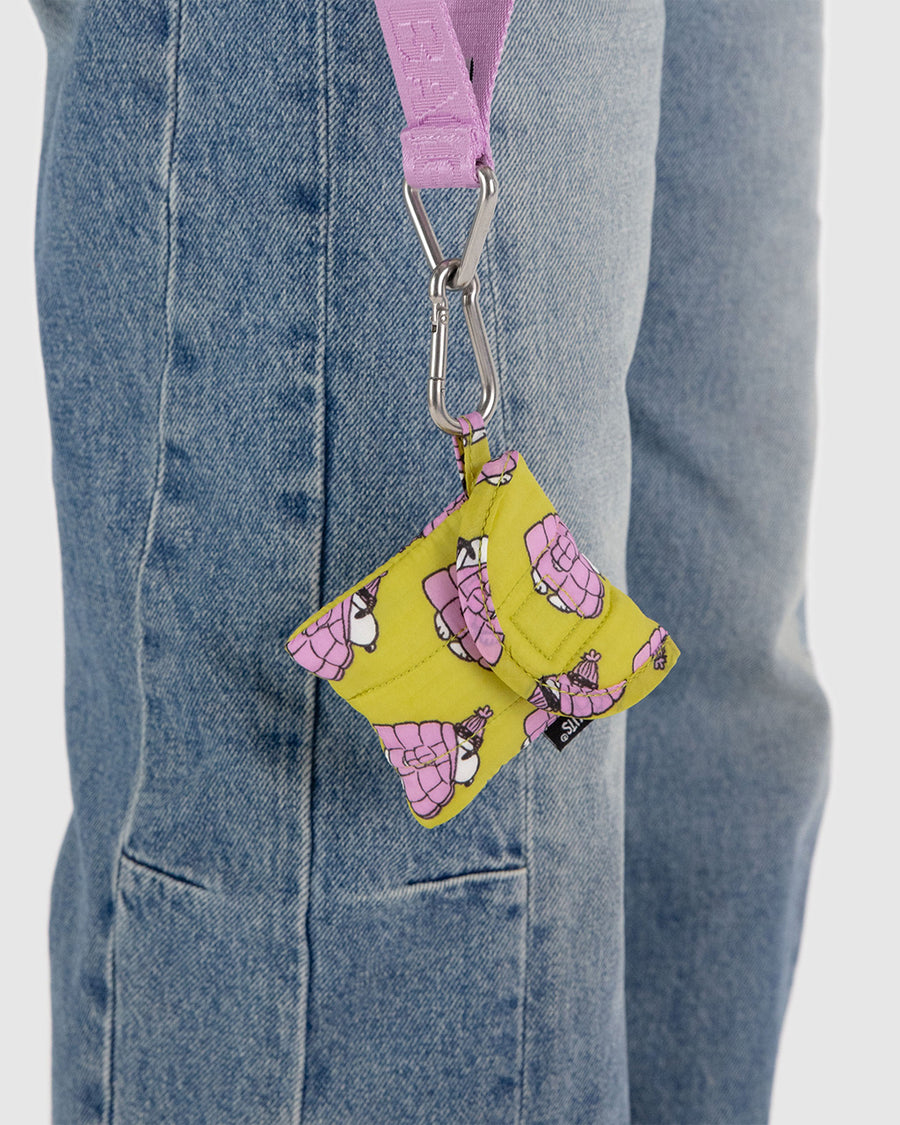 model carrying yellow earbud case with snoopy in a pink puffer coat on a lanyard