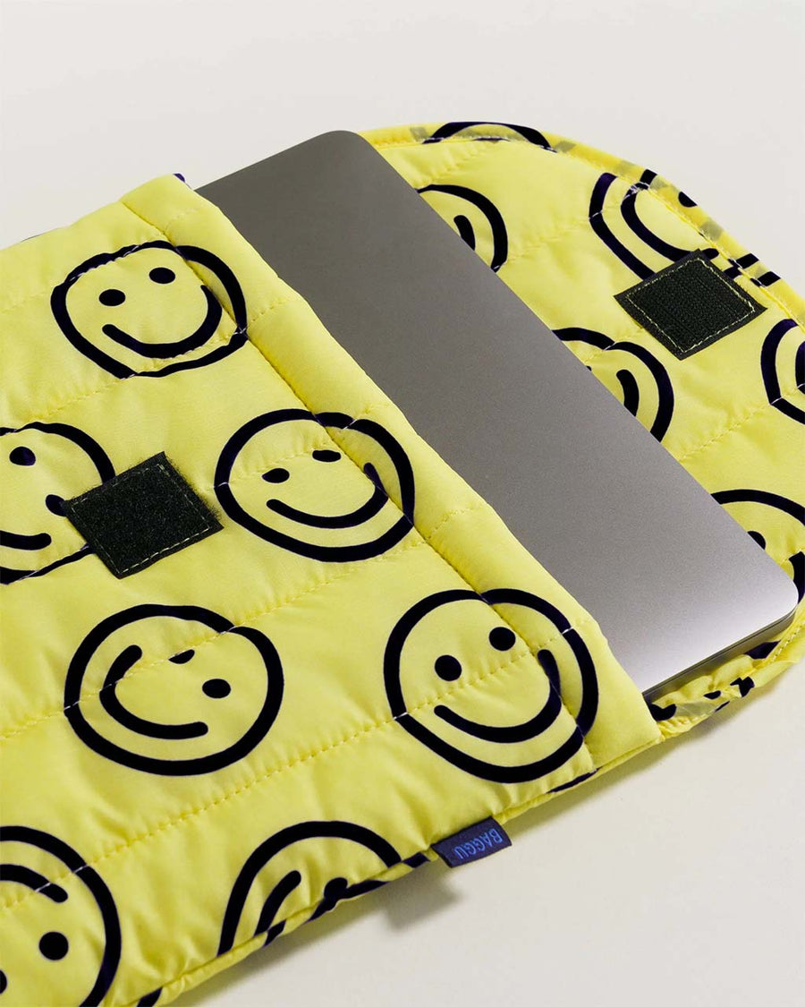 un-velcroed yellow 16 in. laptop sleeve with black smiley face print