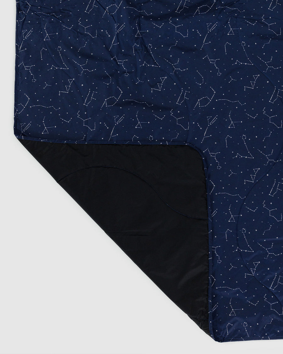 black inside of navy puffy picnic blanket with white constellation print