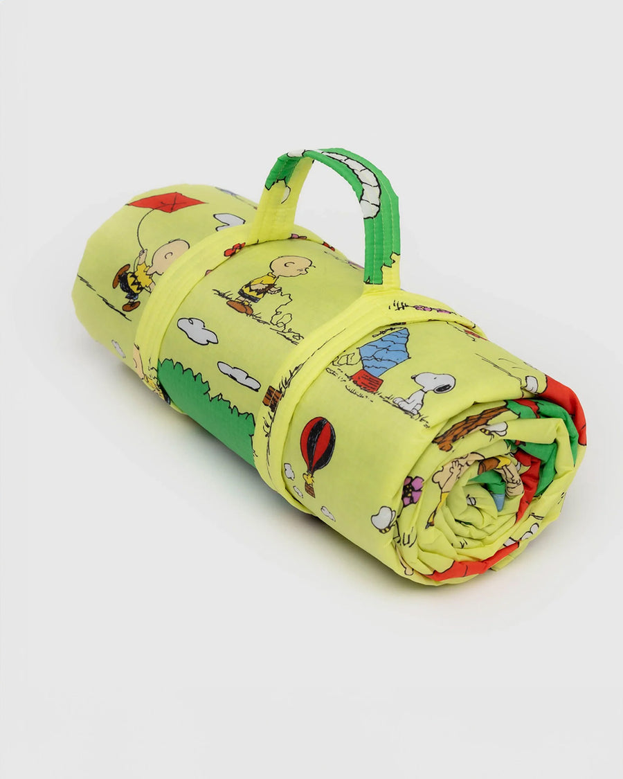 rolled up ellow puffy picnic blanket with charlie brown and friends flying kites