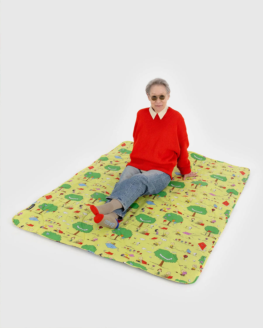 model sitting on yellow puffy picnic blanket with charlie brown and friends flying kites