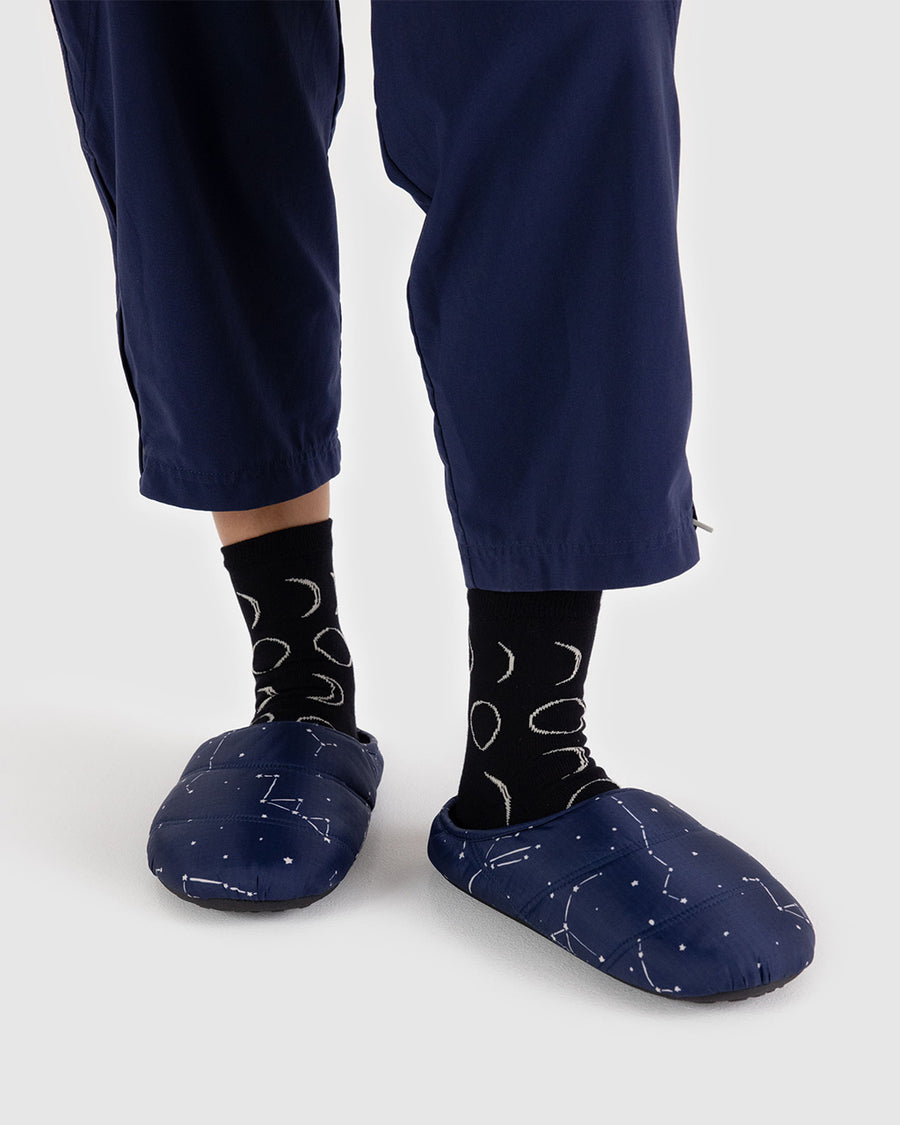 model wearing navy blue puffer slippers with white constellation print