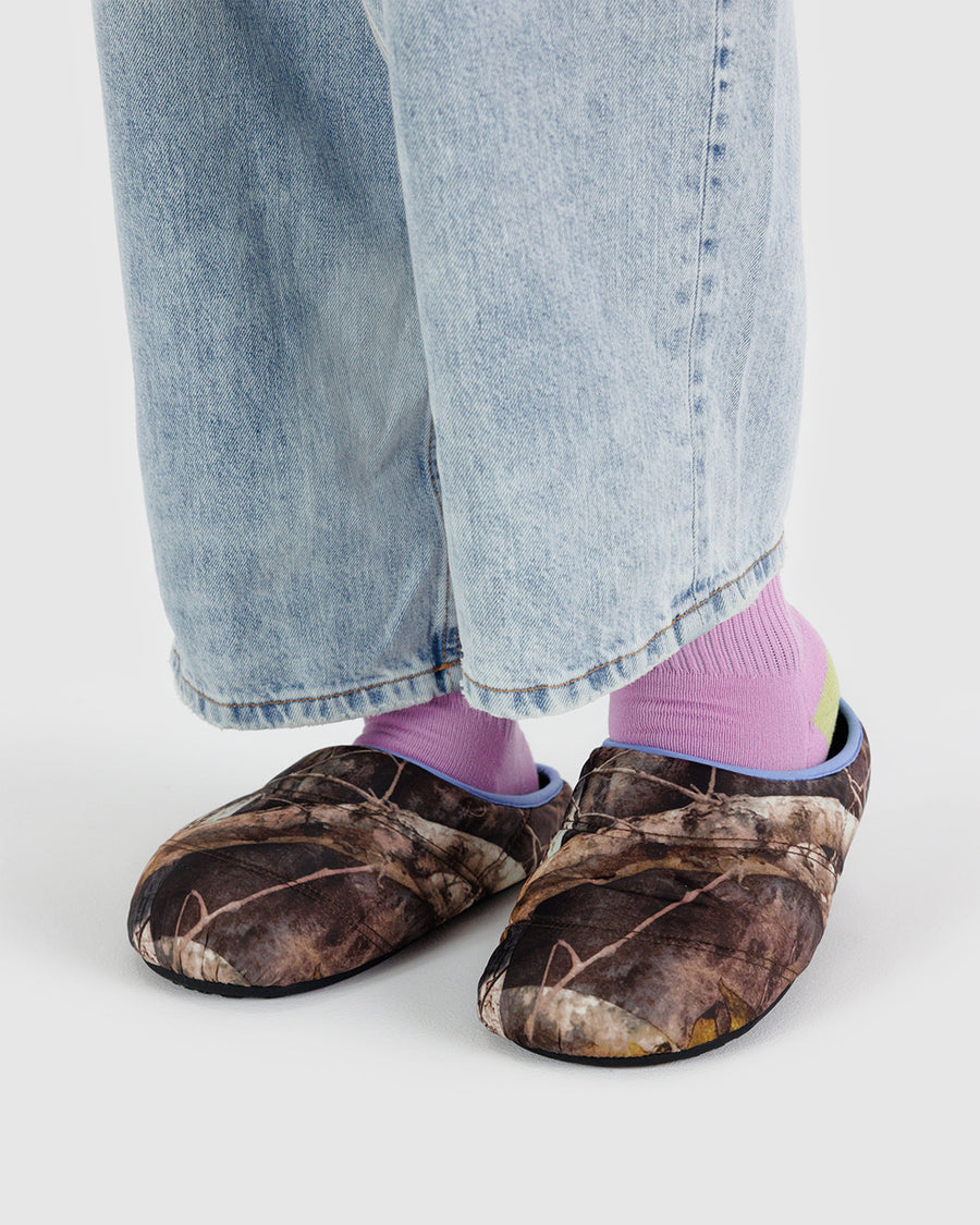 model wearing puffer slippers with realistic forest print and periwinkle trim