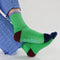 model wearing bright green ribbed crew socks with periwinkle, brown and black accents