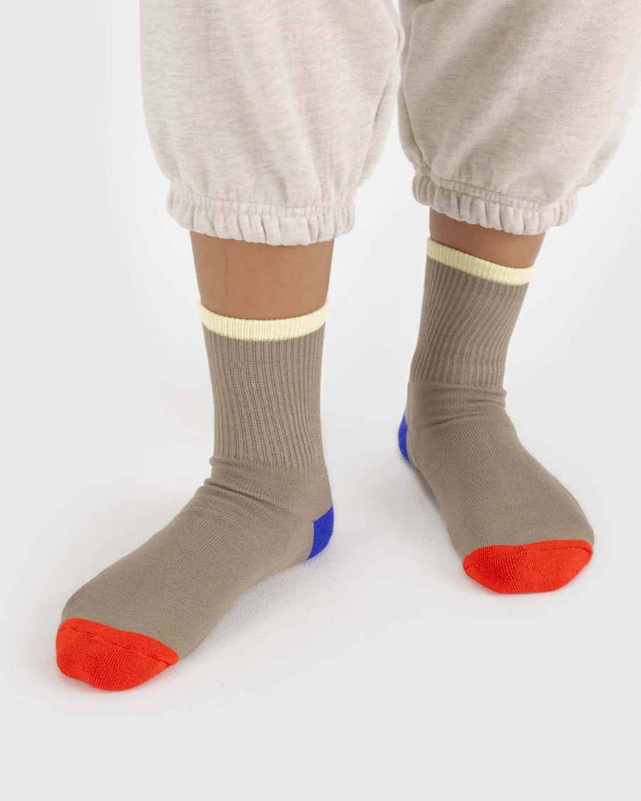 model wearing taupe ribbed socks with bright red, blue and pale yellow trim