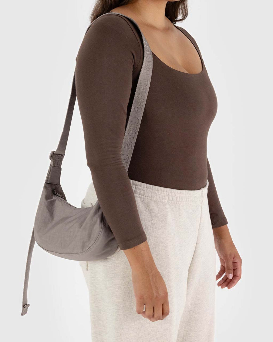 model wearing taupe small nylon crescent bag