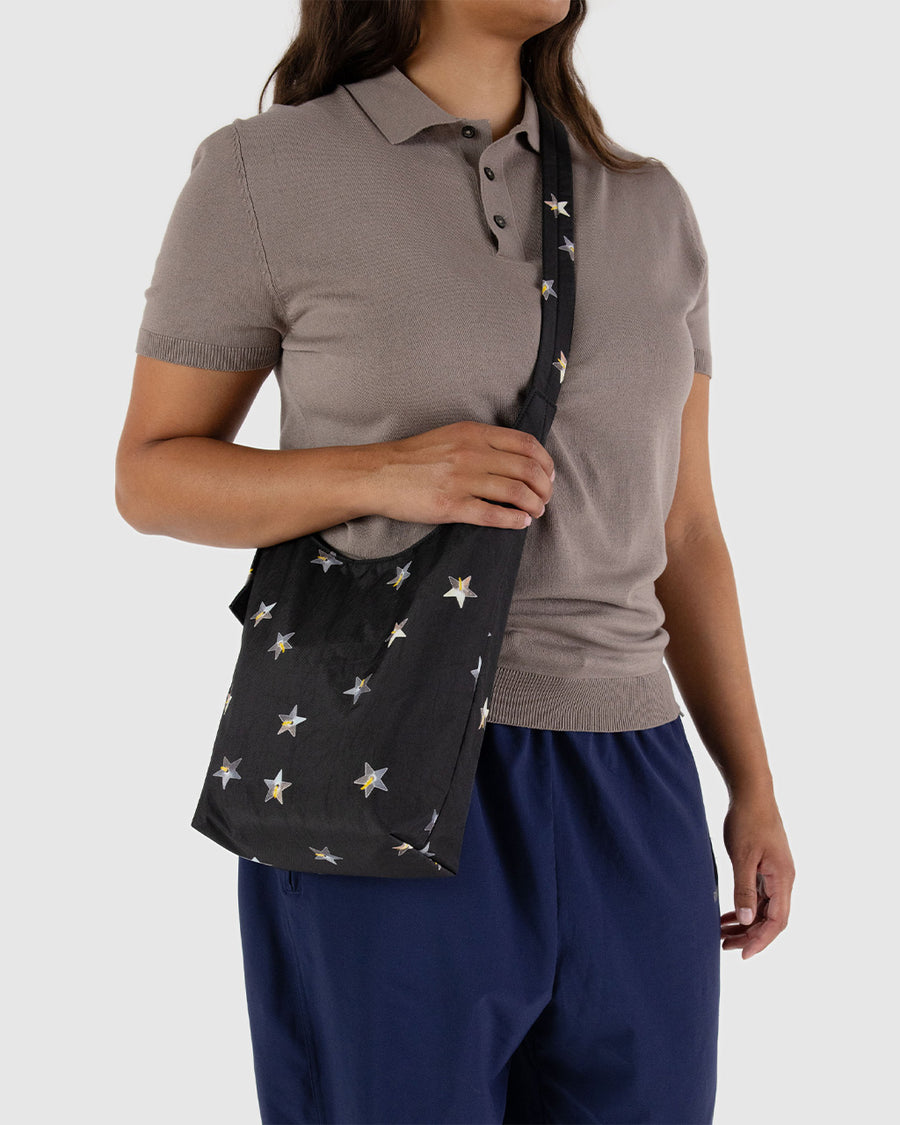 model carrying black small sling bag with metallic star print