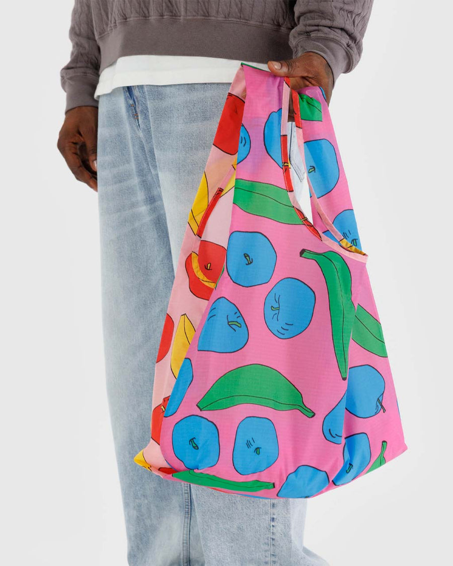 model holding pink standard baggu with colorful apple and banana print