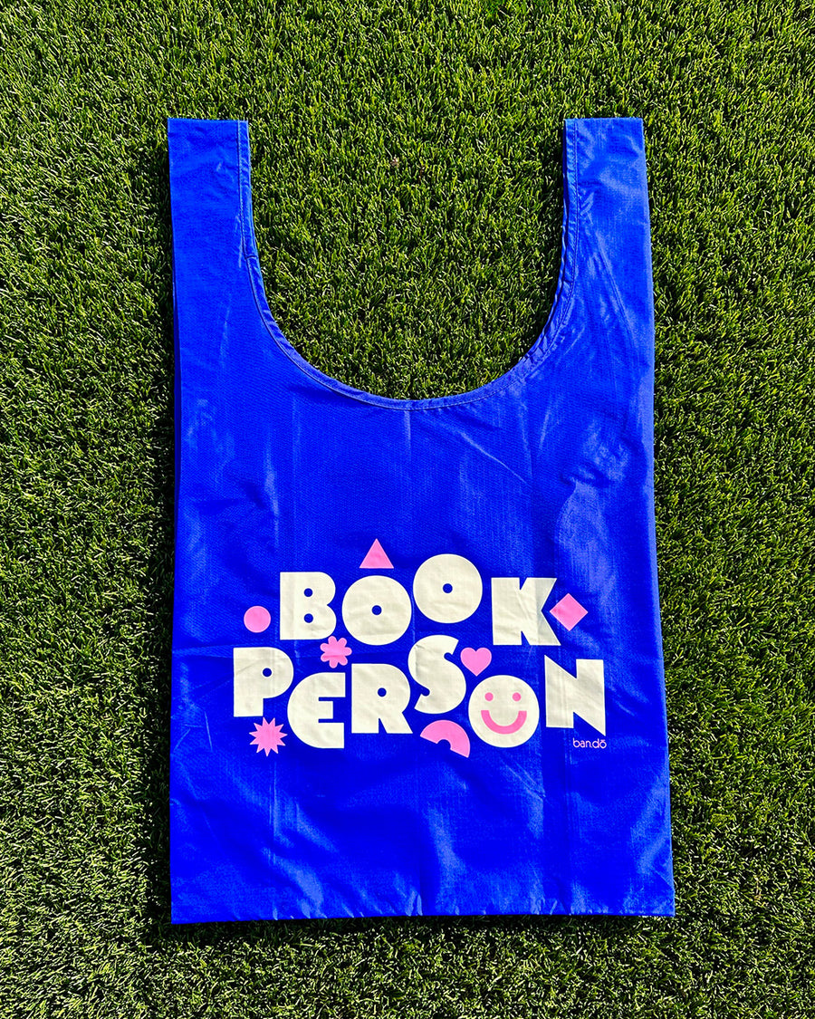 royal blue standard baggu with white 'book person' and pink shapes across the front