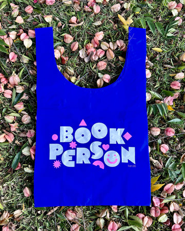 royal blue standard baggu with white 'book person' and pink shapes across the front