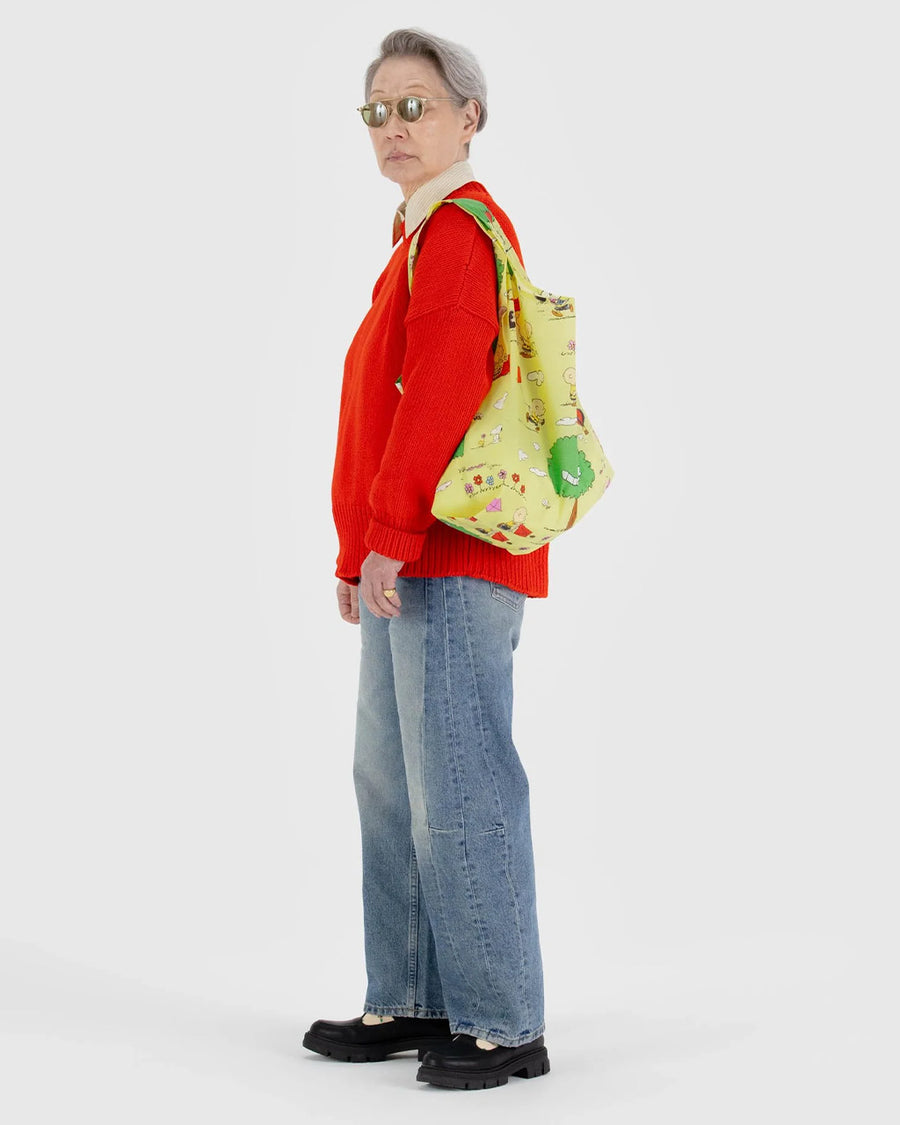 model carrying yellow standard baggu with snoopy and friends flying a kite