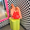 pink standard baggu with red 'lets have some fun' across the front on a flower shaped stool leaning on a black and white checkered wall