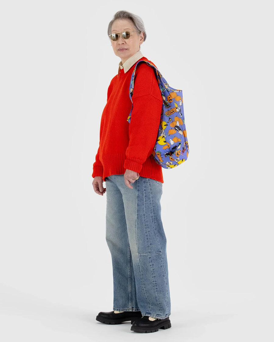 model holding blue standard baggu with peanuts characters in halloween costumes and surrounded by jack o'lanterns and pumpkin