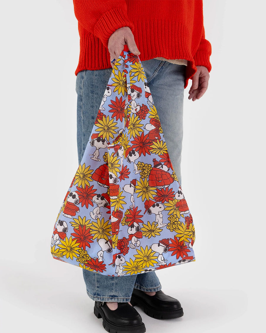 model holding periwinkle standard baggu with all over red and yellow floral and joe cool print