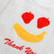 side view of side view of white standard baggu with fruit smiley (strawberry eyes and banana smile) with red 'thank you'