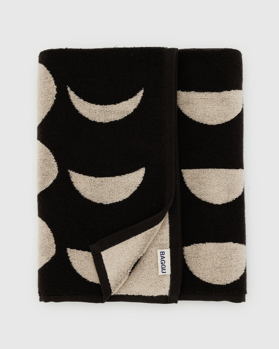 folded reversible bath towel with black and cream moon phase print