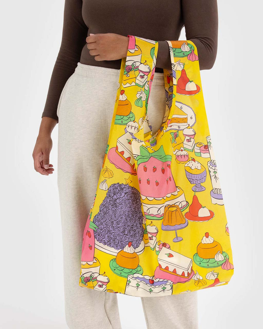 model holding yellow big baggu with colorful cake and pastry print