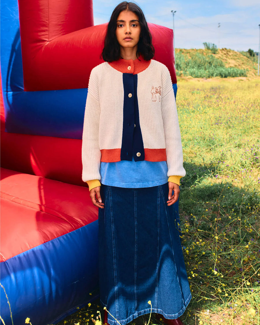 model wearing cream knit cardigan with yellow sleeve cuffs, coral trim and navy button front with embroidered couple on bust