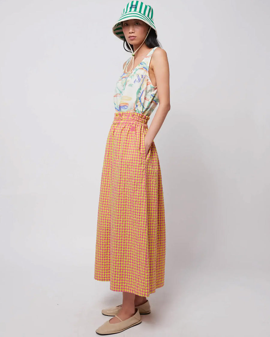 model wearing pink and yellow gingham maxi skirt with smocked waist and side pockets