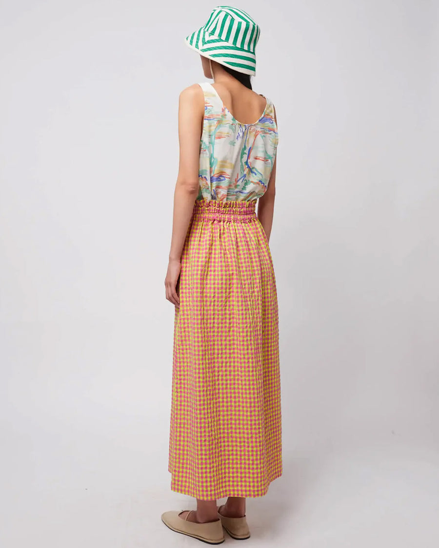back view of model wearing pink and yellow gingham maxi skirt with smocked waist and side pockets