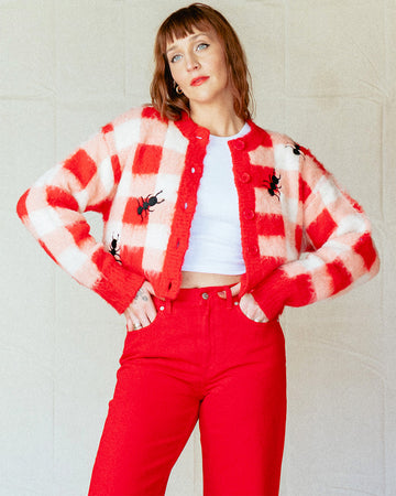model wearing cropped red, pink and white gingham cardigan with all over embroidered ant print
