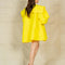 back view of model wearing yellow dress with flowy skirt, oversized sleeves and collar and large yellow bow on the front