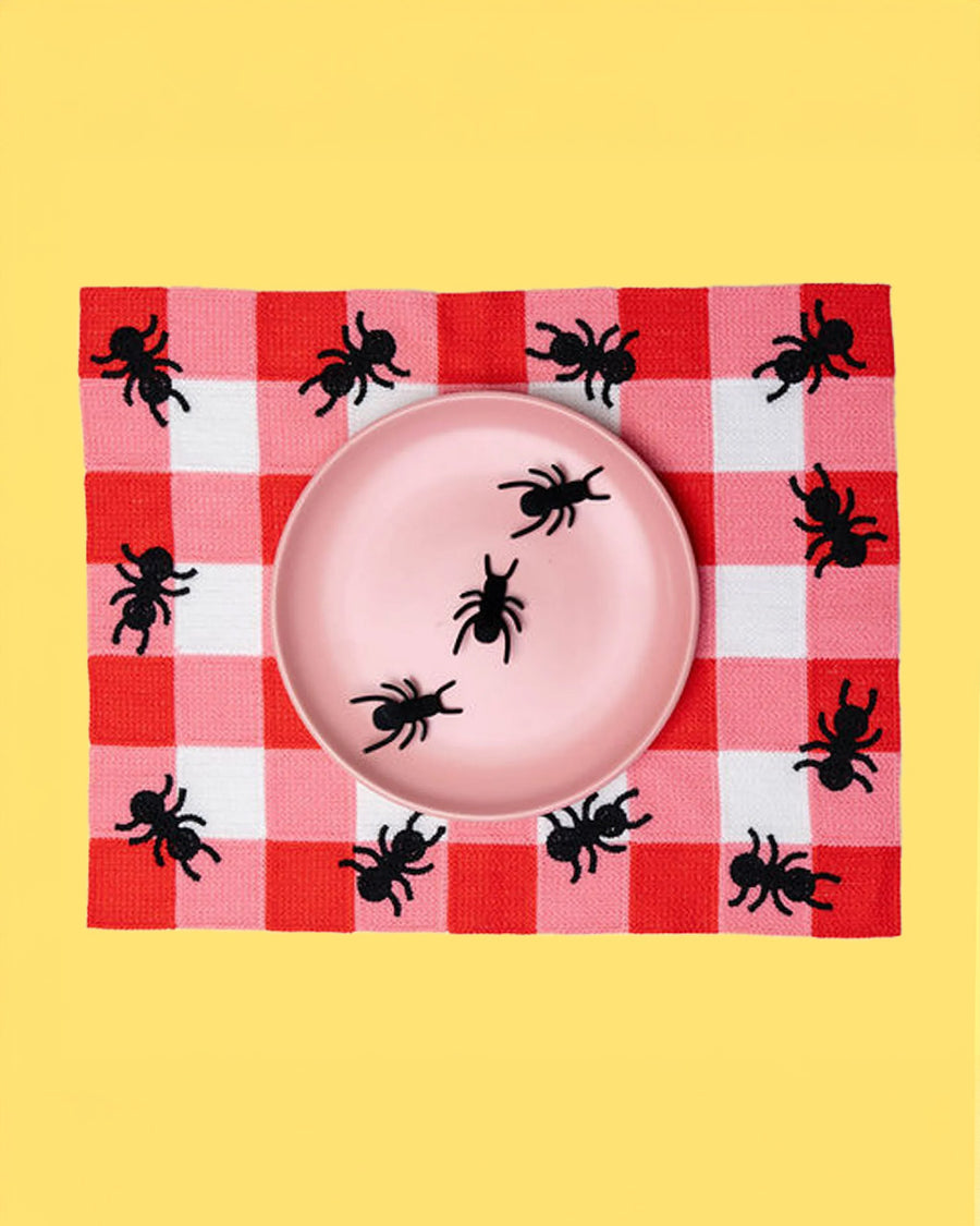 pink and white plaid placemat with black ant border on a yellow ground