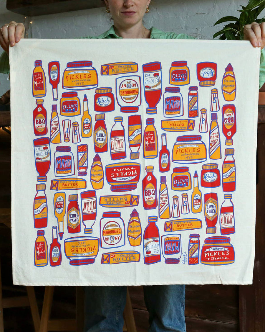 model holding tea towel with different condiment bottles