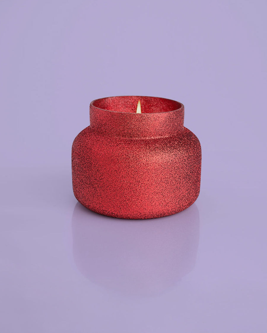 lit 19 oz. red glitter candle with gold lid