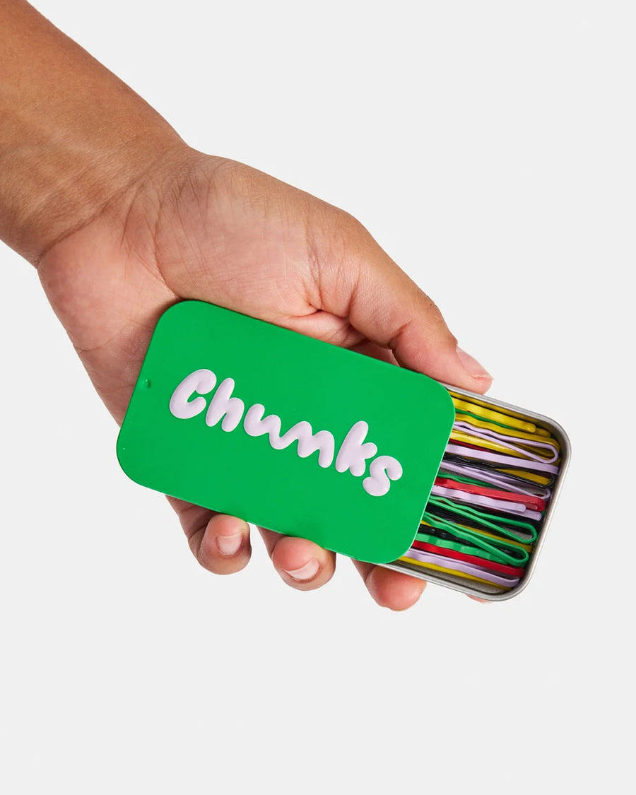 model holding green tin of colorful bobby pins