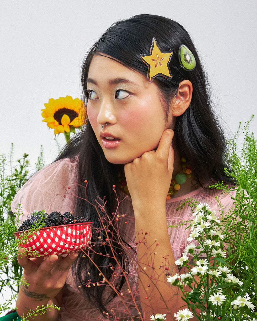 model wearing set of three realistic fruit print clips: yellow starfruit, kiwi, and cherries