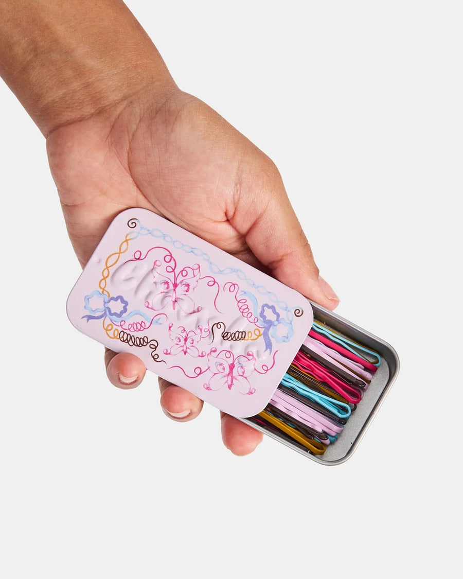 model holding lilac butterfly printed tin of colorful bobby pins