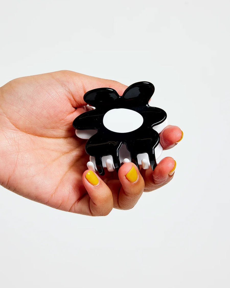 model holding black and white flower shaped hair claw