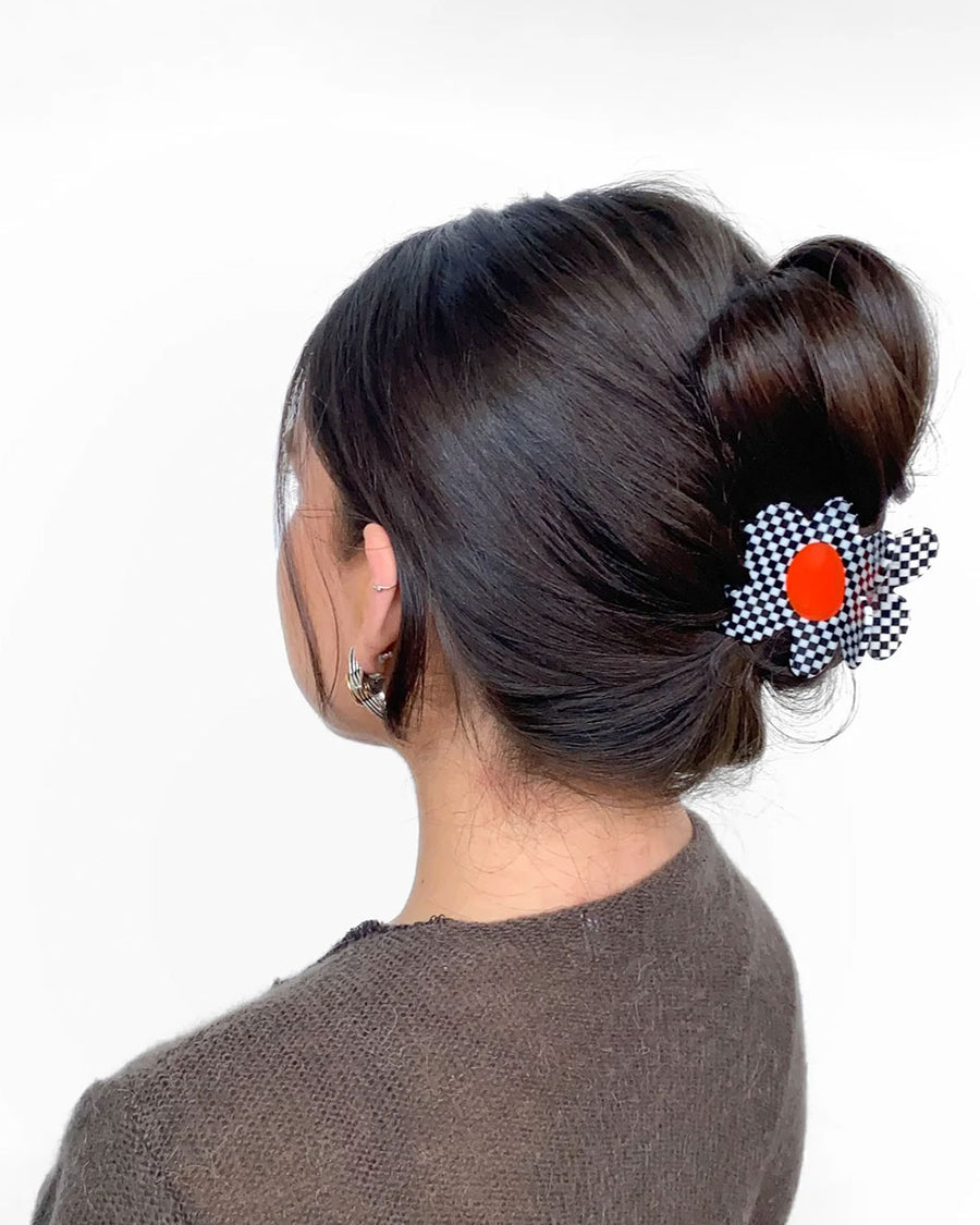 model wearing black and white checkered flower hair claw with orange center