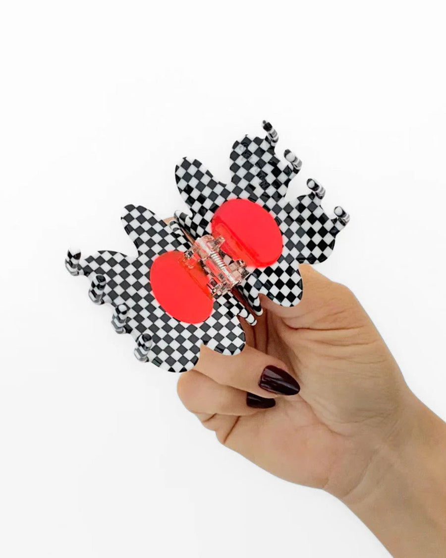 model opening black and white checkered flower hair claw with orange center