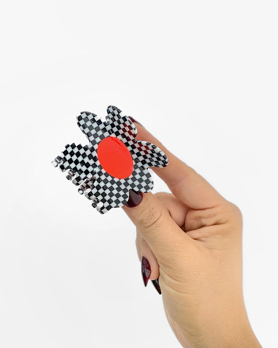 model holding black and white checkered flower hair claw with orange center