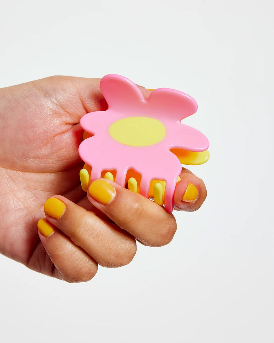 model holding pink and yellow flower shaped hair claw