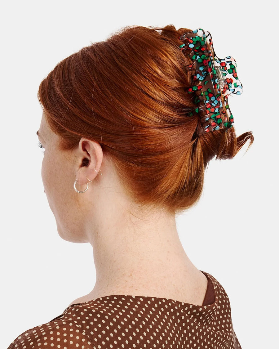 model wearing clear large hair claw with blue, green and red confetti coloring