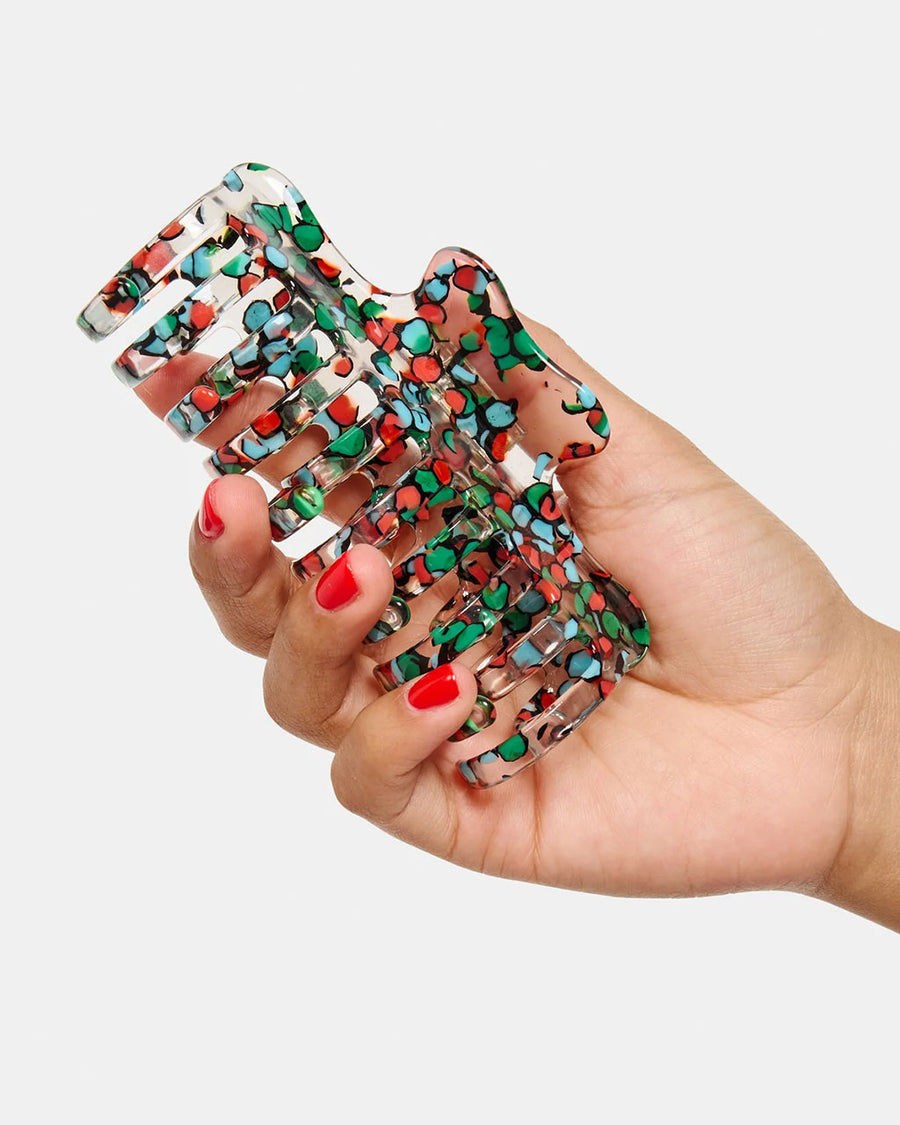 model holding clear large hair claw with blue, green and red confetti coloring