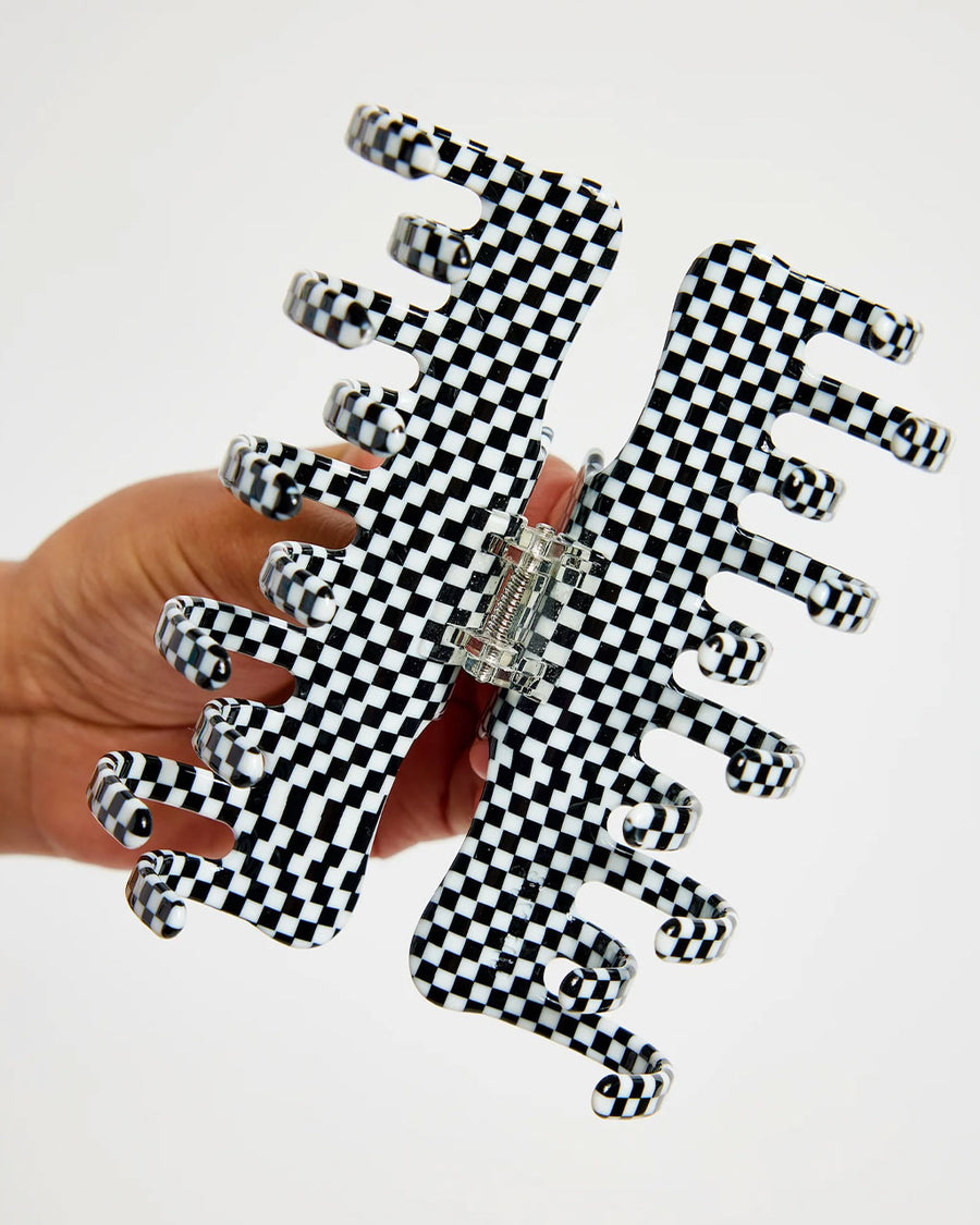 model opening large black and white checkered hair claw with double row of teeth