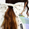 up close of model wearing white oversized hair bow clip with all over black ant design