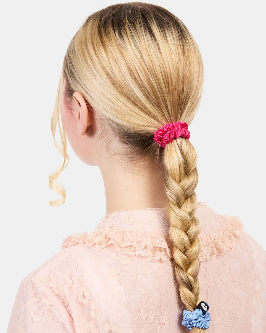 model wearing set of three skinny silk hair scrunchies: grey, hot pink and periwinkle