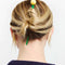 model wearing green hair stick with yellow ball on the end