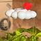 white cloud shaped houseplant waterer with red heart charm in a potted plant