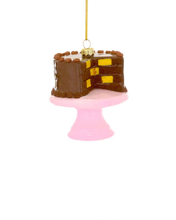 glass chocolate cake ornament with yellow and brown checkered inside on a pink cake stand