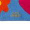 up close of blue rectangle scarf with colorful tassels on the end and yellow diamond, orange flower and pink heart design