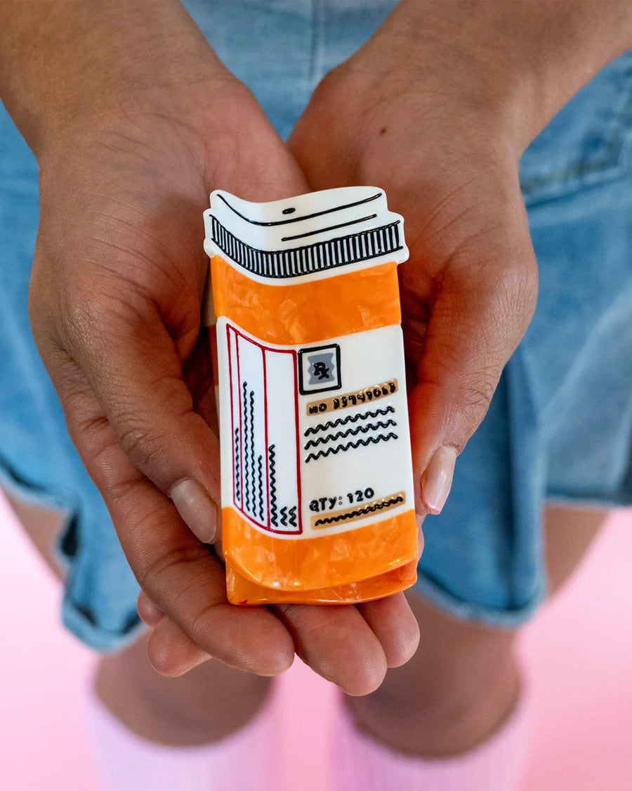model holding orange prescription bottle hair claw