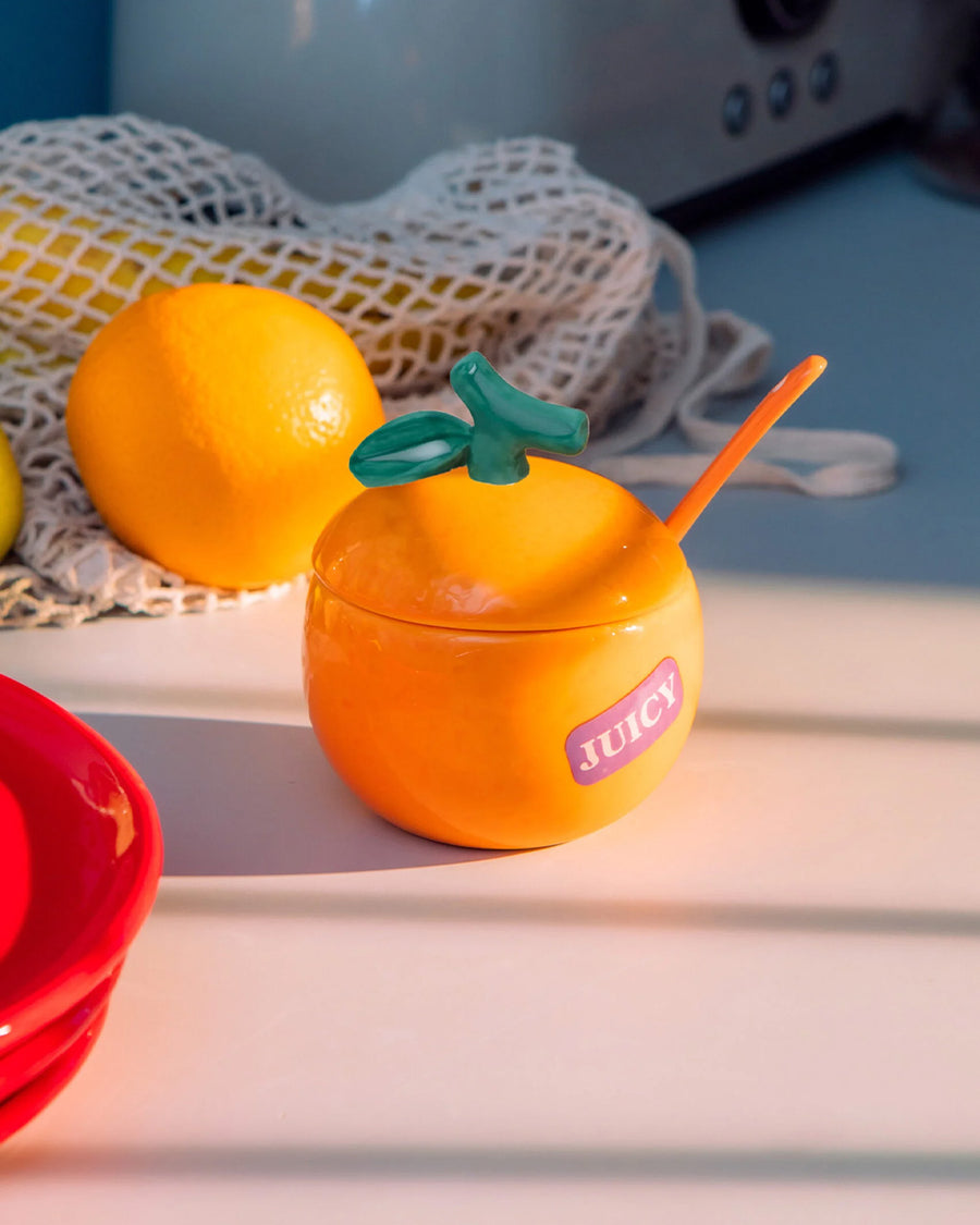 orange ceramic sugar bowl with purple 'juicy' sticker on the side