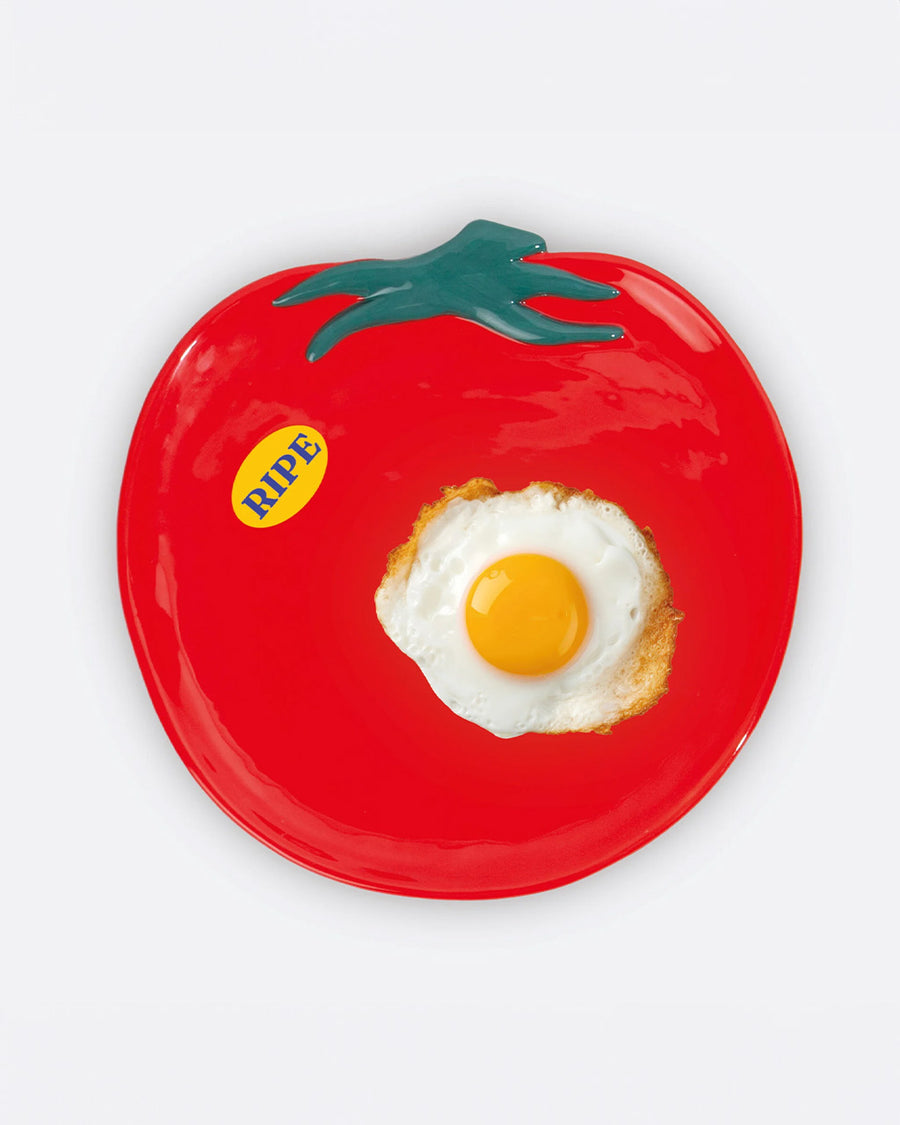 tomato shaped plate with yellow 'ripe' sticker on the left side with an egg on it